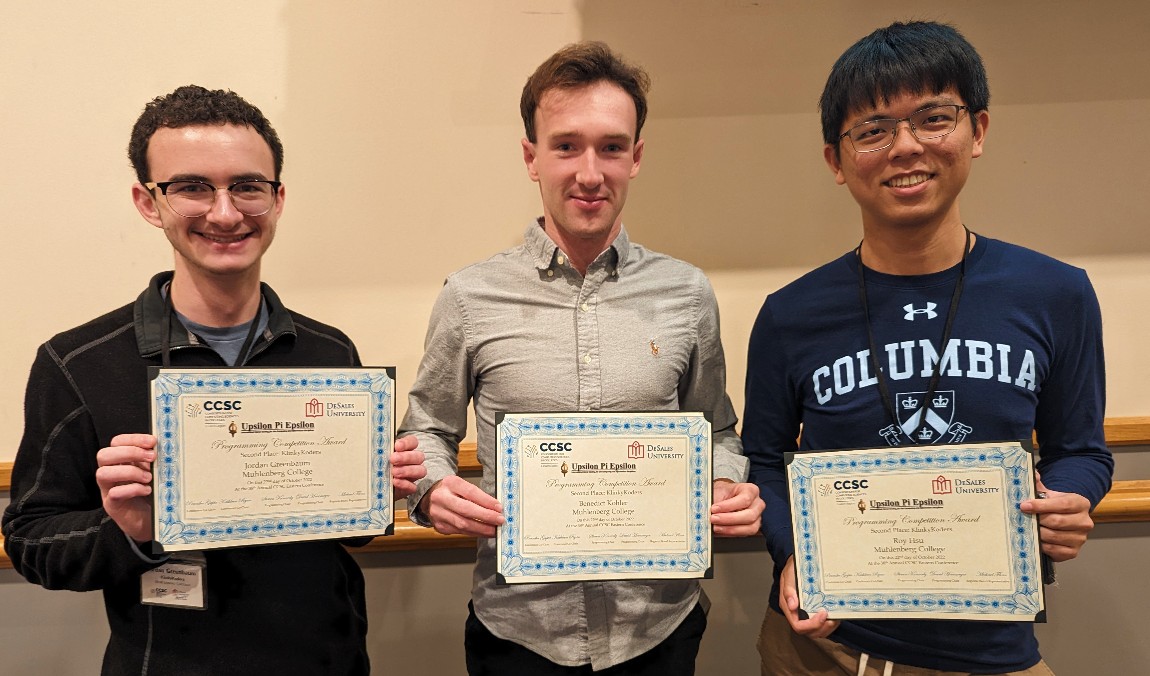 Three male students stand in a row, holding certificates